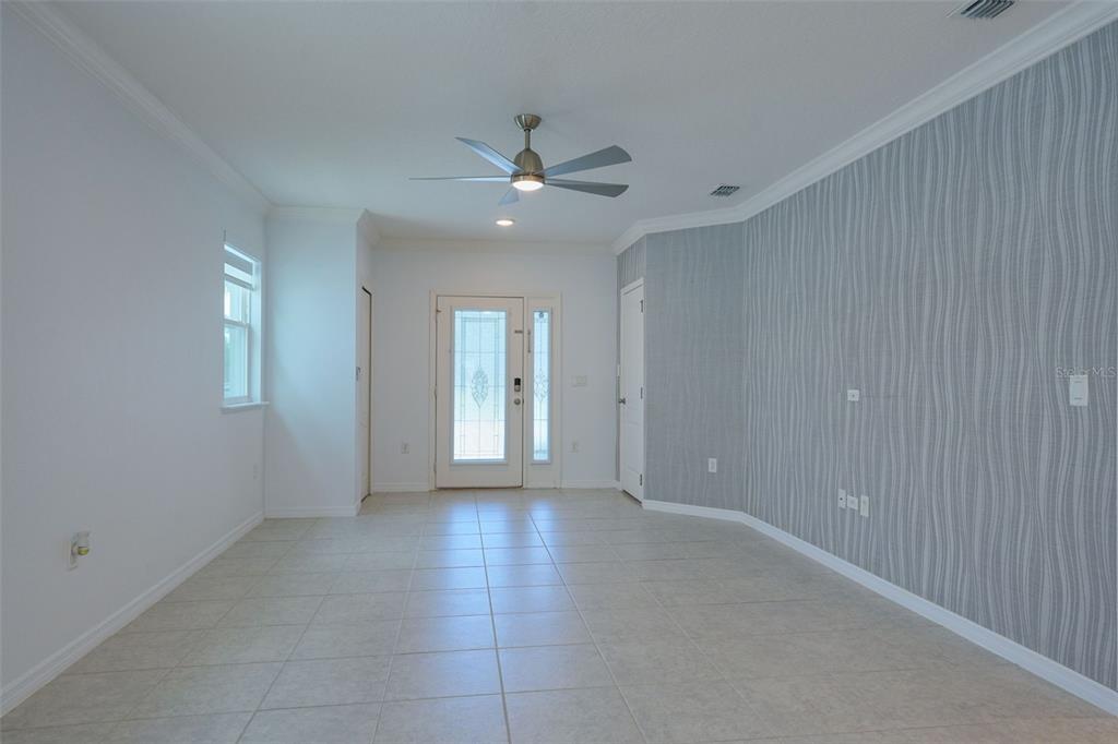 An empty room features light tile flooring, a ceiling fan, and a gray patterned accent wall — 173 VILLAVISTA COURT, DAVENPORT, FL
