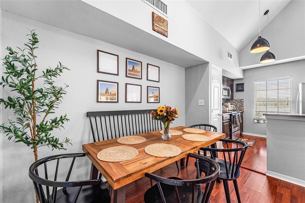 A dining area features a wooden table, black chairs, a bench, and wall art — 9638 LAKE CHASE ISLAND WAY UNIT 9638, TAMPA, FL