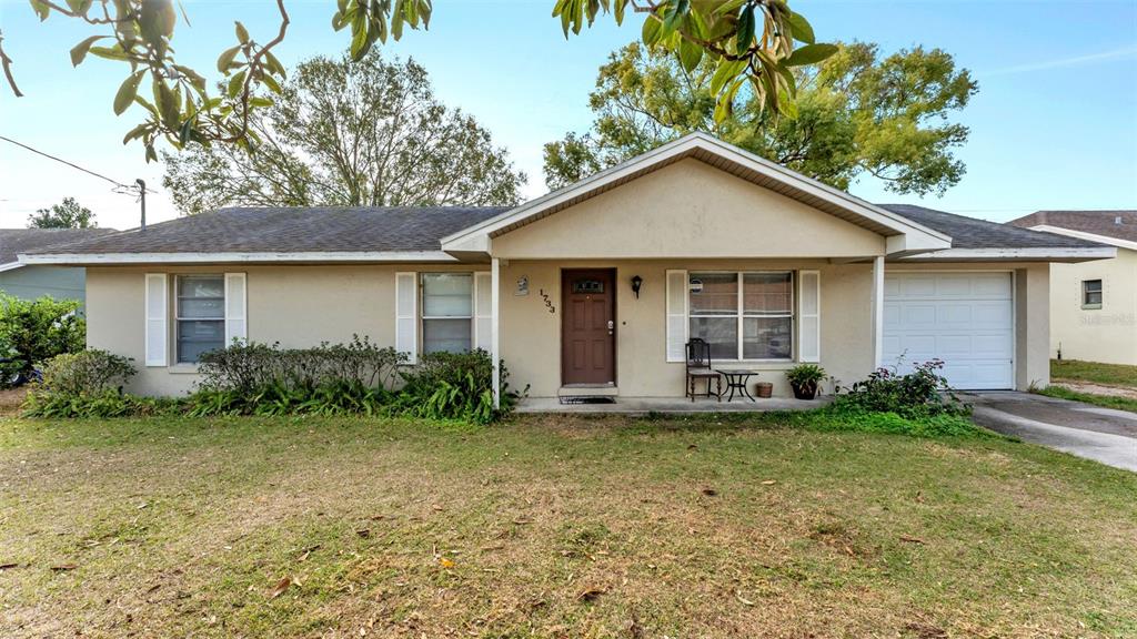 A single-story house with a beige exterior, a brown front door, and an attached garage — 1733 SANDALWOOD CIRCLE SW, WINTER HAVEN, FL