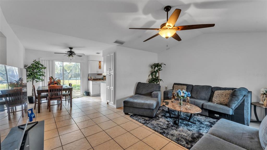 A living room with tile floors, a ceiling fan, and a dining area in the background — 1733 SANDALWOOD CIRCLE SW, WINTER HAVEN, FL
