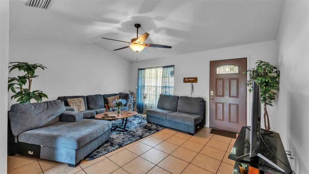 A living room features a grey sectional sofa, a coffee table, and a front door — 1733 SANDALWOOD CIRCLE SW, WINTER HAVEN, FL