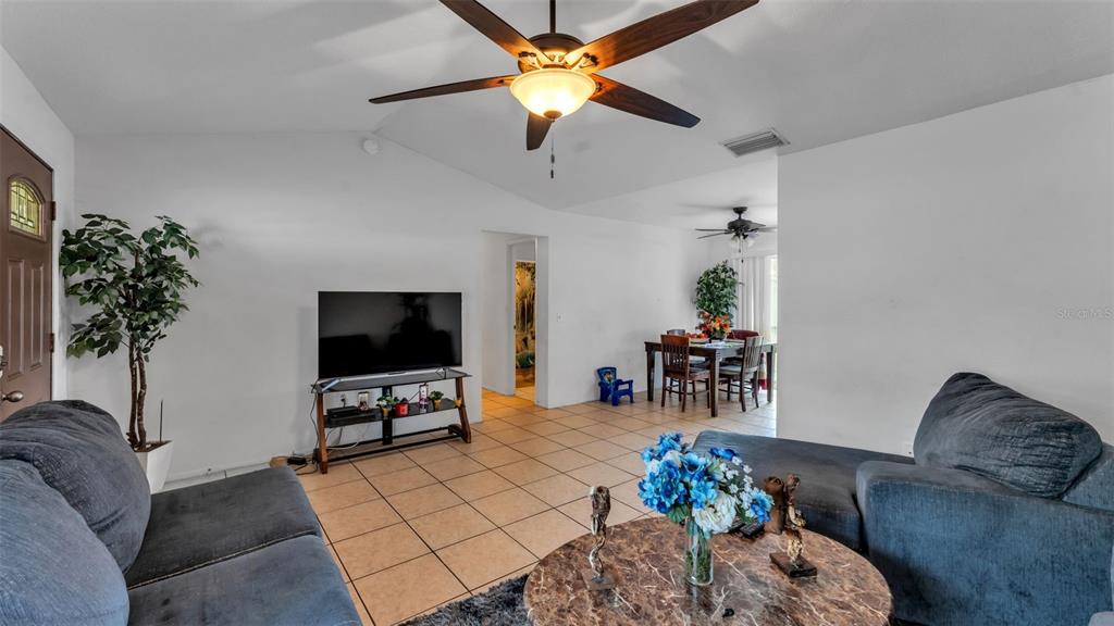 A living room with tile floors, a ceiling fan, a television, and a dining area — 1733 SANDALWOOD CIRCLE SW, WINTER HAVEN, FL