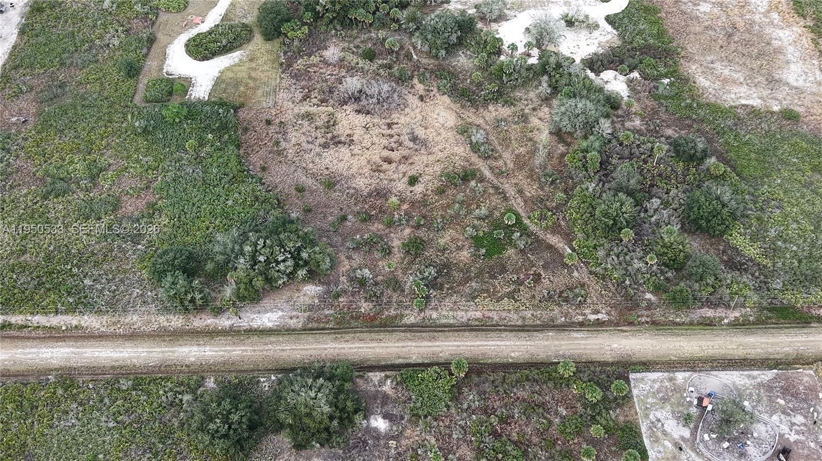An aerial view shows a vacant, brush-covered lot bordered by a dirt road — 21867 NW 276TH, Okeechobee FL 34972, OKEECHOBEE, FL