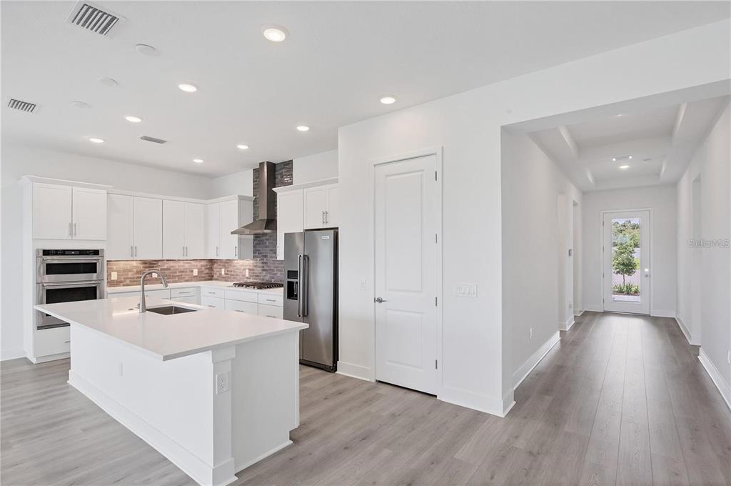 A paved entryway leads to a blue front door on a light green house exterior — 705 ANEGADA LANE, SARASOTA, FL