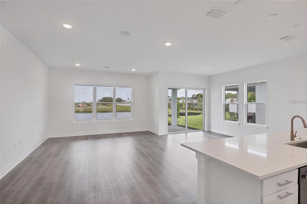 An open-concept living room and kitchen with light wood floors and a large center island — 705 ANEGADA LANE, SARASOTA, FL