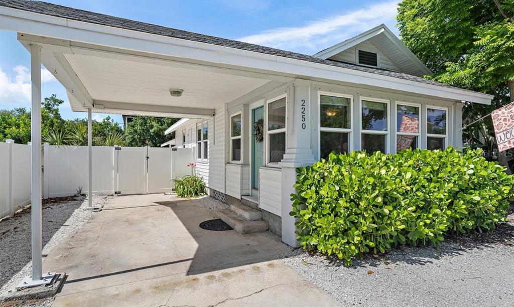 A white house exterior features a covered carport, a front door, and a large hedge — 2250 ARLINGTON STREET, SARASOTA, FL
