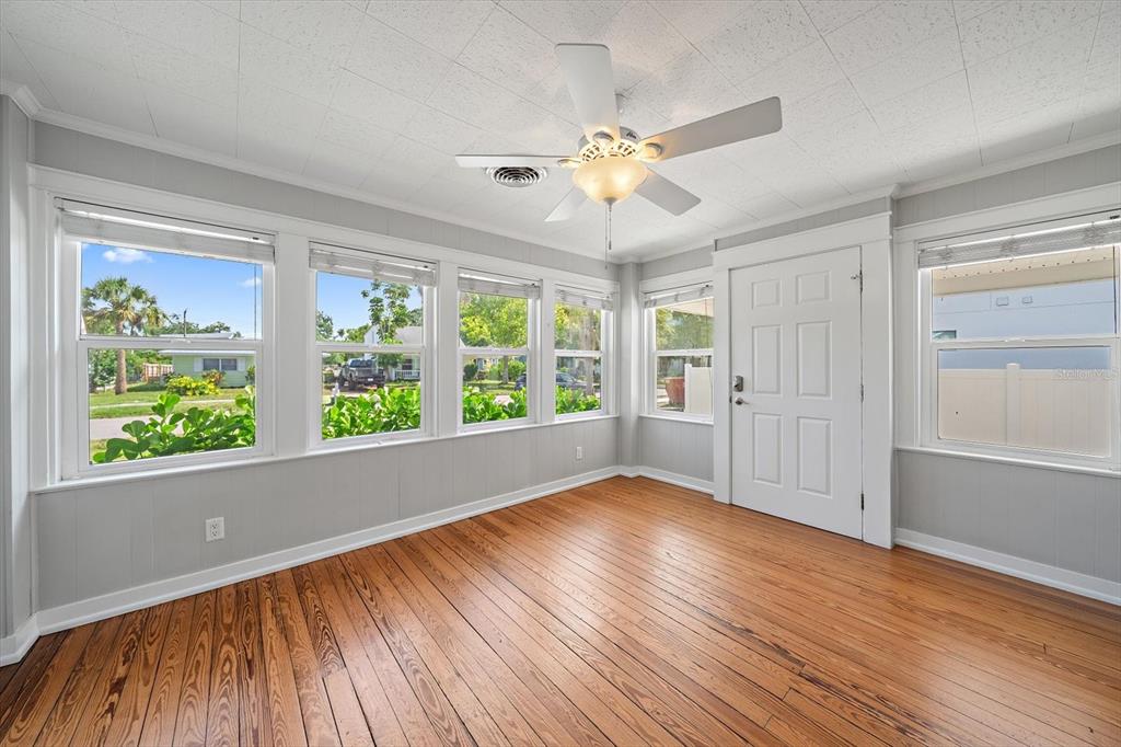 A sunroom with gray paneled walls, hardwood floors, a ceiling fan, and multiple windows — 2250 ARLINGTON STREET, SARASOTA, FL