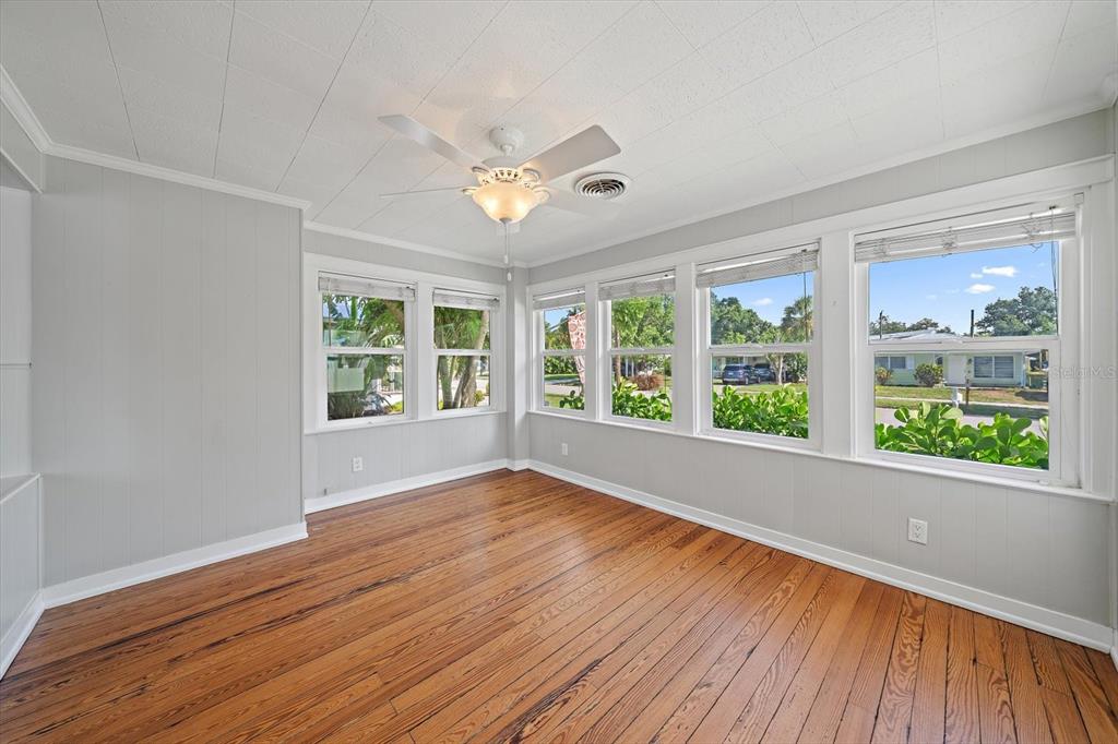 A sunroom with light gray walls, wood flooring, a ceiling fan, and multiple windows — 2250 ARLINGTON STREET, SARASOTA, FL