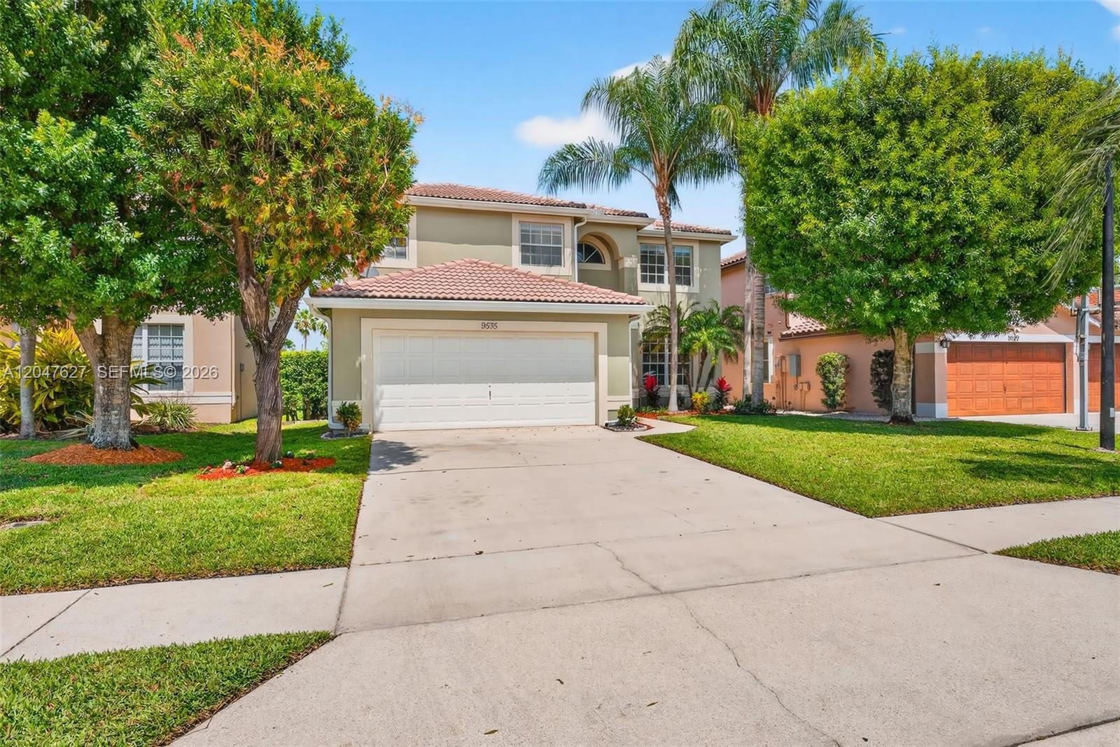 A two-story suburban house features a tan stucco exterior, a tiled roof, and a garage — 9535 Fox Trot Ln, Boca Raton FL 33496, BOCA RATON, FL
