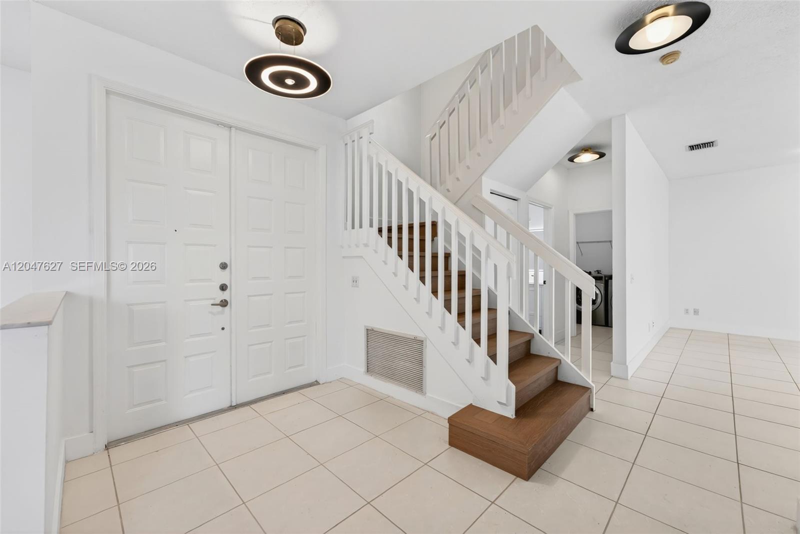 A bright entryway features white double doors, a wooden staircase, and light-colored tile flooring — 9535 Fox Trot Ln, Boca Raton FL 33496, BOCA RATON, FL