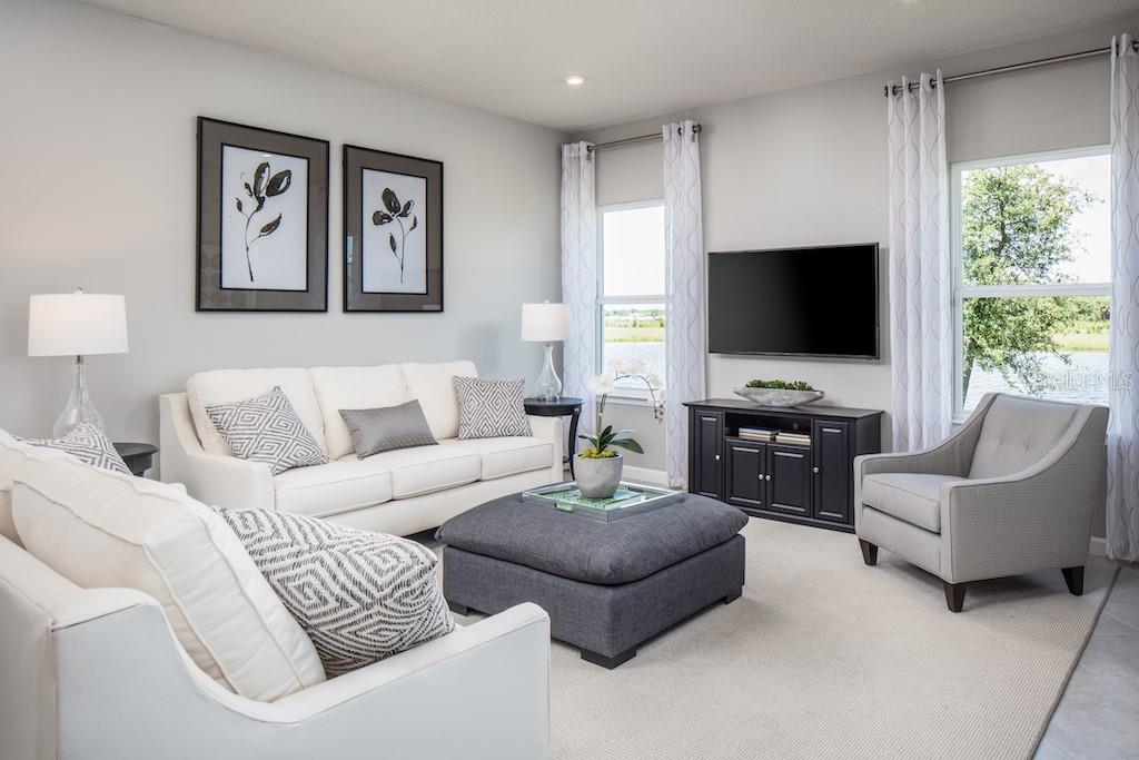 A living room features a white sofa, a gray ottoman, and a television on a console — 1079 OCEAN LODGE ROAD, LADY LAKE, FL