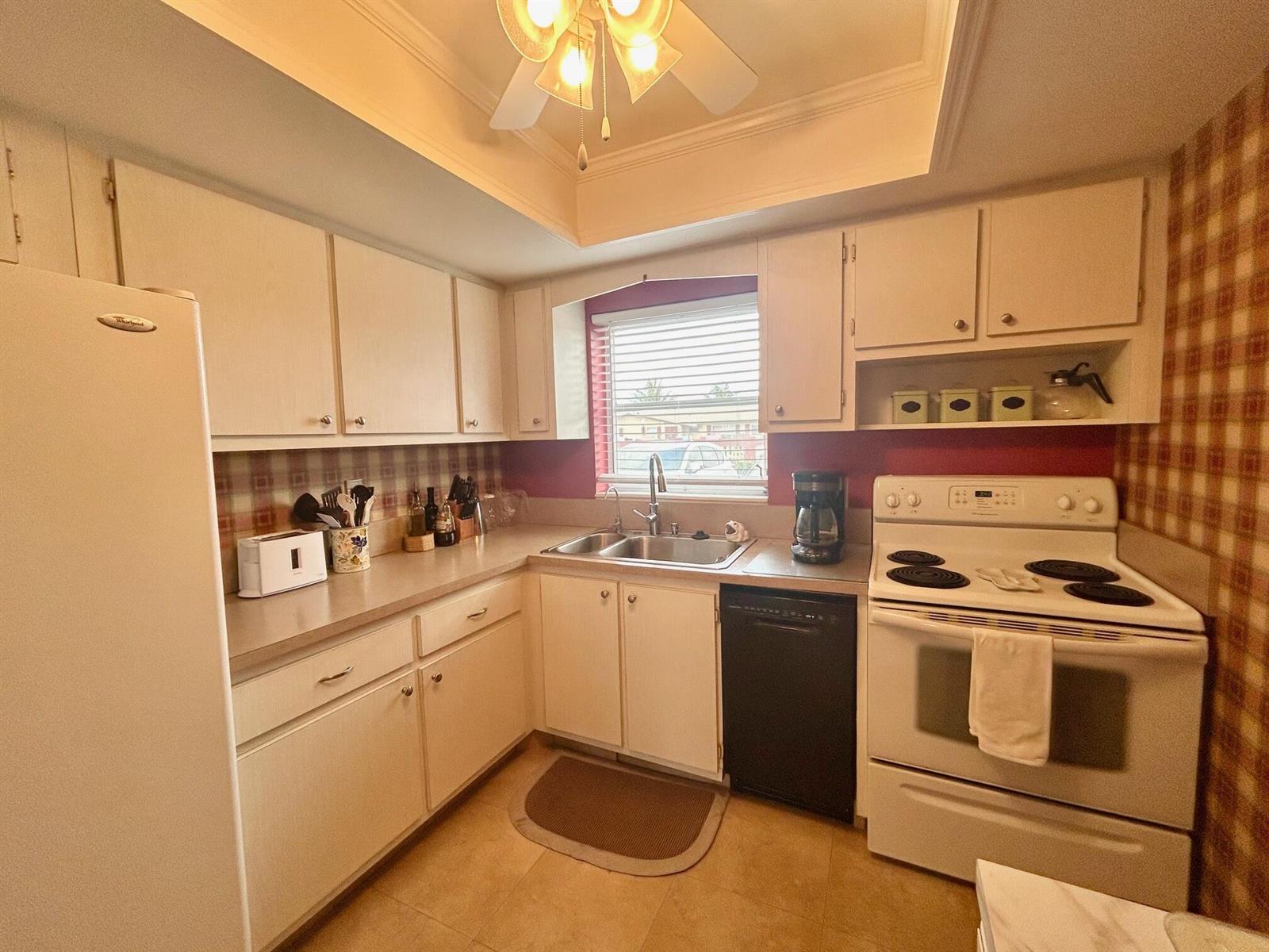 A kitchen features white cabinetry, a double sink, a black dishwasher, and a white stove — 2990 Crosley Drive E # G, West Palm Beach FL 33415, WEST PALM BEACH, FL