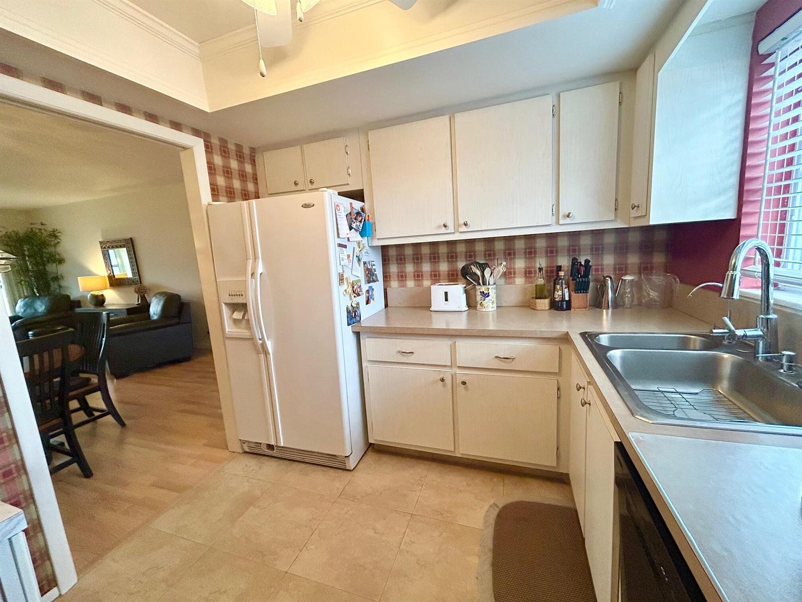 A kitchen features white cabinets, a white refrigerator, a double sink, and plaid wallpaper — 2990 Crosley Drive E # G, West Palm Beach FL 33415, WEST PALM BEACH, FL