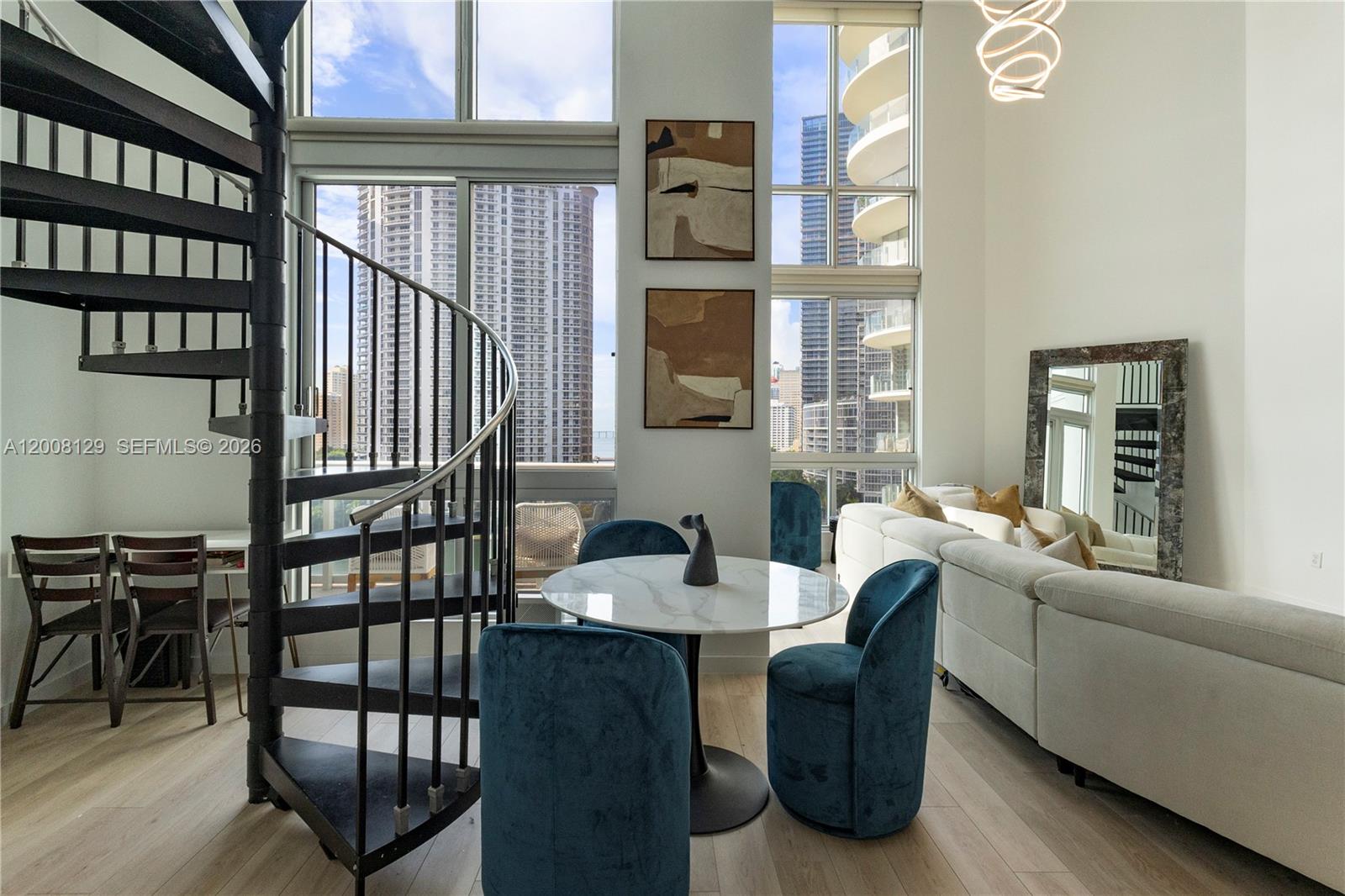 A modern living room features a spiral staircase, floor-to-ceiling windows, and a dining area — 300 S Biscayne Blvd # 1014, Miami FL 33131, MIAMI, FL
