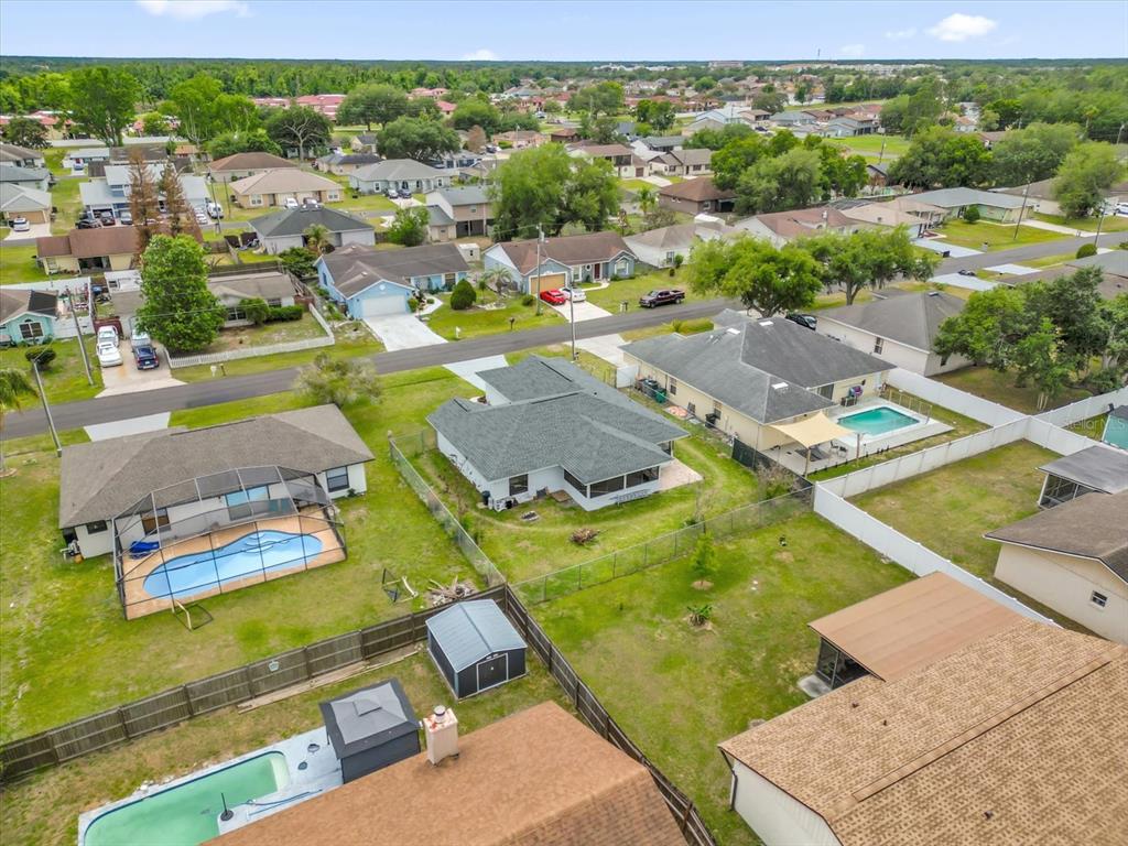 An aerial view shows several suburban houses with swimming pools and fenced backyards — 615 MCKINLEY COURT, KISSIMMEE, FL