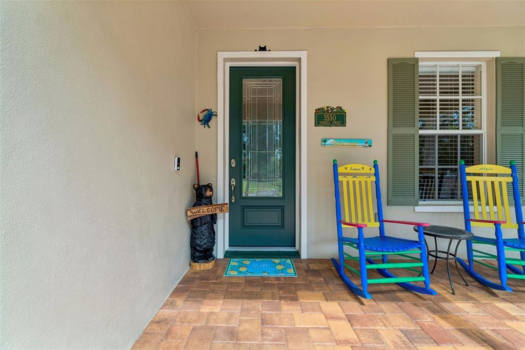 A front porch features a green door, two colorful rocking chairs, and a bear statue — 3550 FERRELL STREET, NEW PORT RICHEY, FL