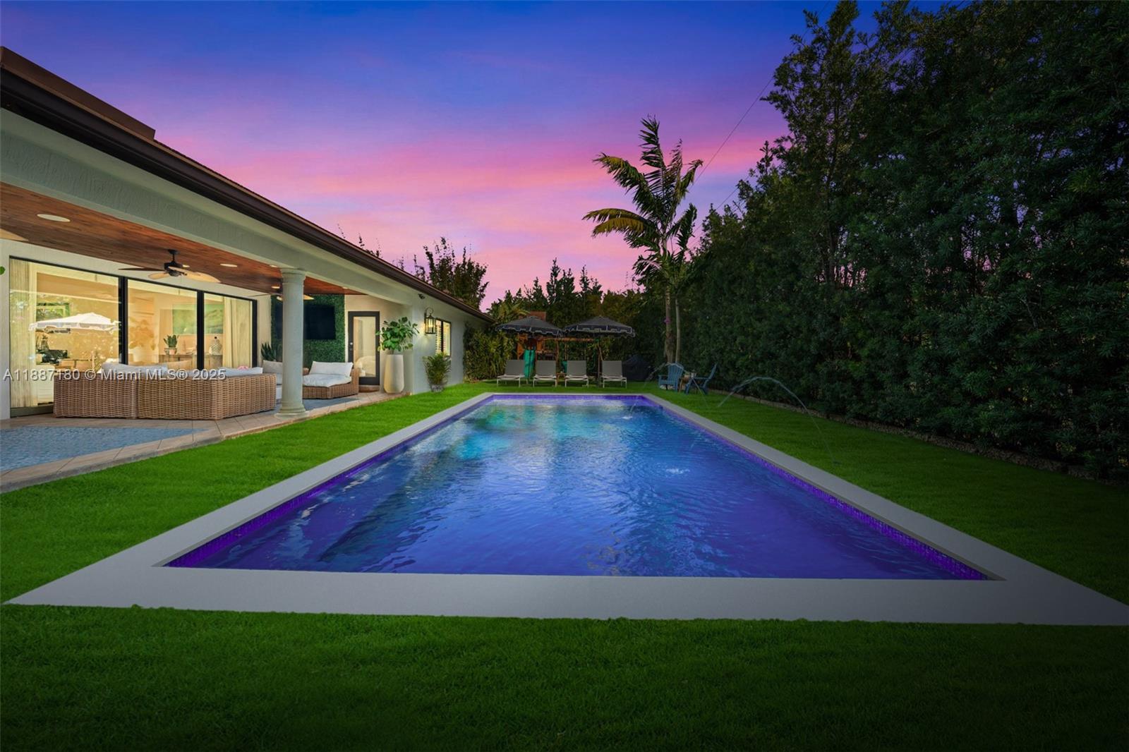 A rectangular swimming pool sits in a grassy backyard next to a covered patio — 6420 SW 63rd Ter, South Miami FL 33143, SOUTH MIAMI, FL