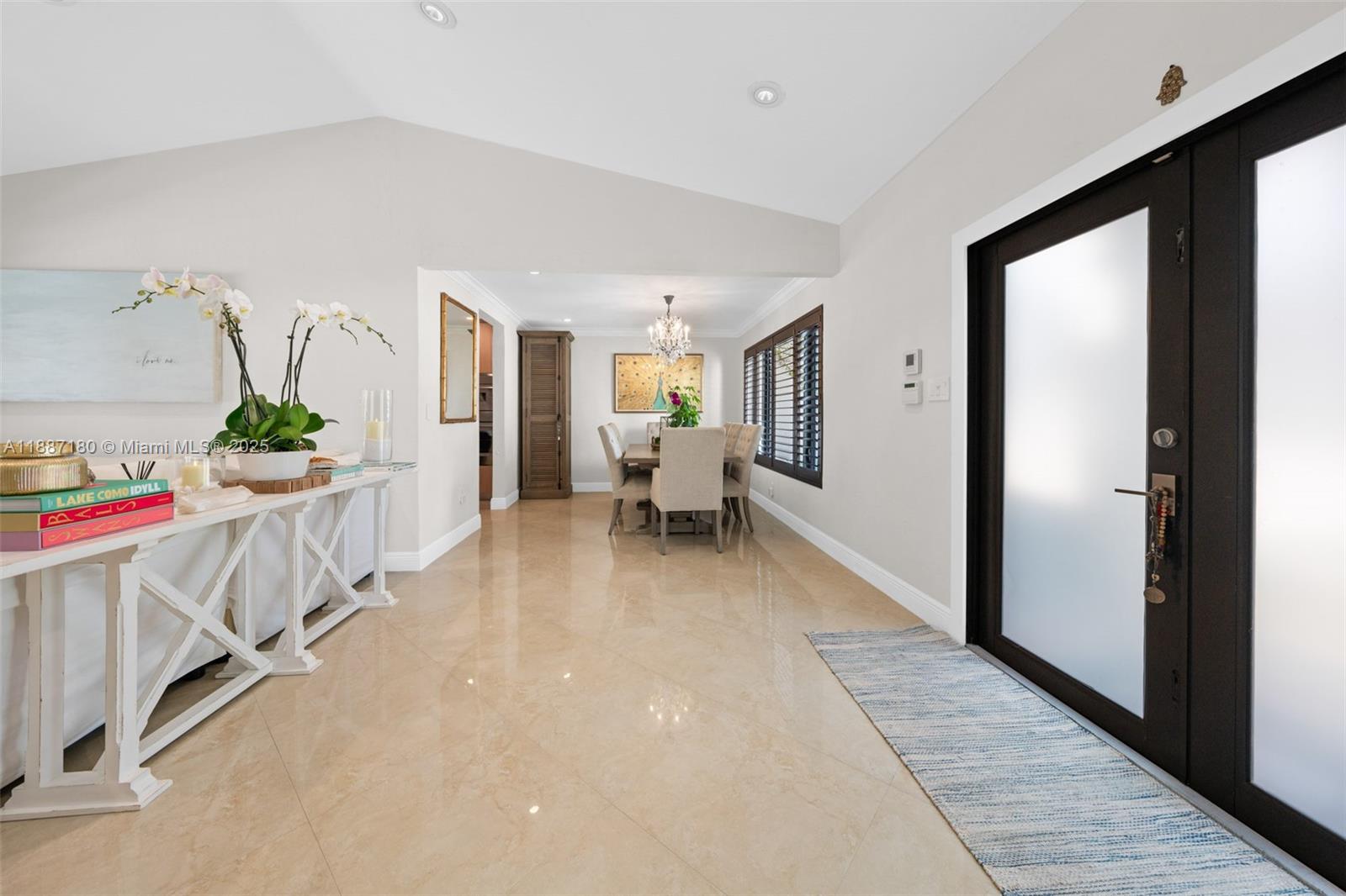 A bright entryway with beige tile floors leads into a dining area with a chandelier — 6420 SW 63rd Ter, South Miami FL 33143, SOUTH MIAMI, FL