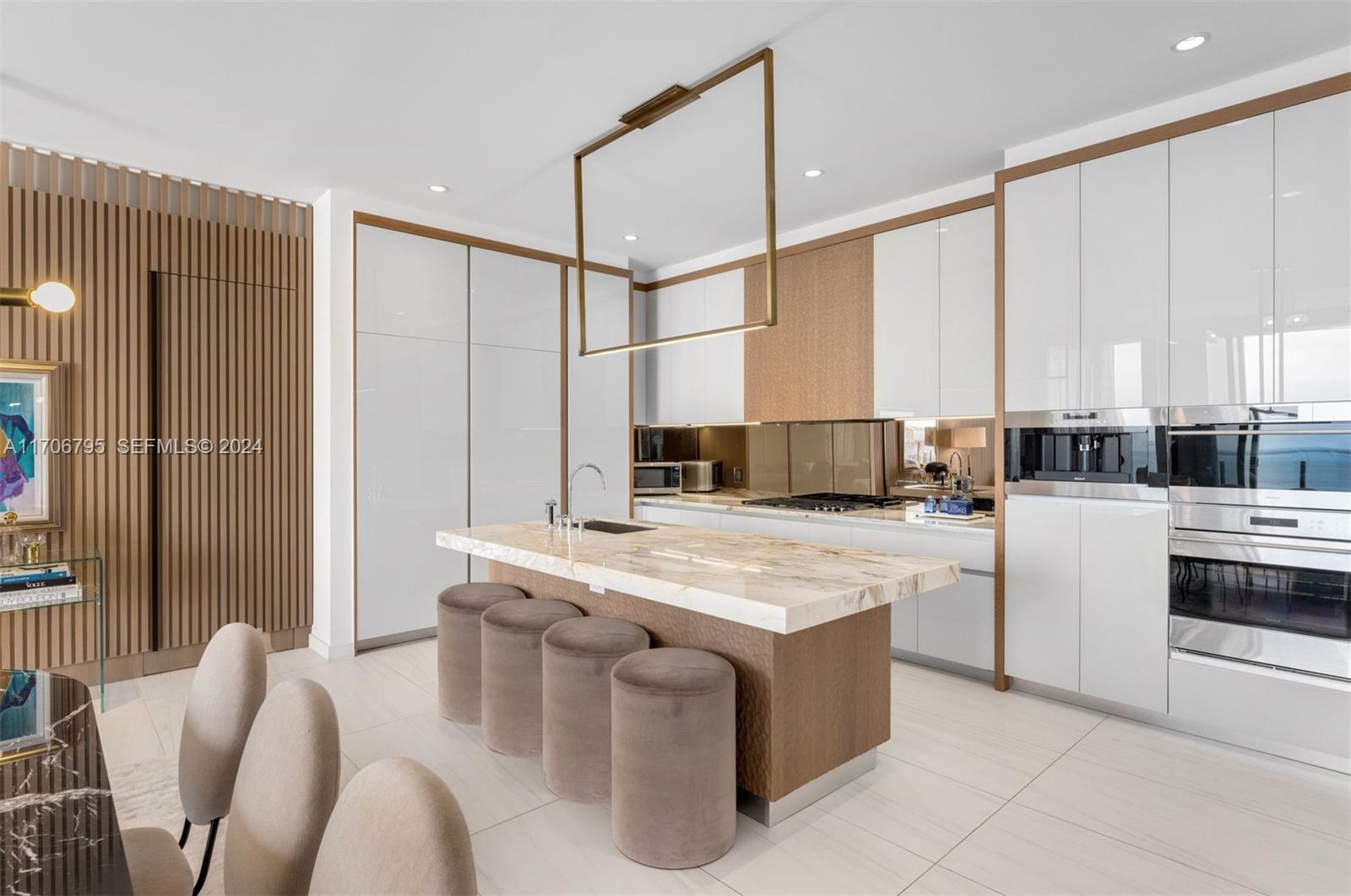 A modern kitchen features a marble-topped island with four stools and sleek white cabinetry — 2811 S Bayshore Dr, Miami FL 33133, MIAMI, FL