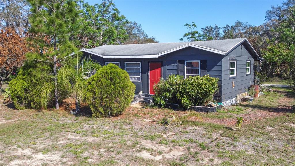 A dark gray single-story house with a bright red front door sits on a lot — 3726 KENILWORTH BOULEVARD, SEBRING, FL