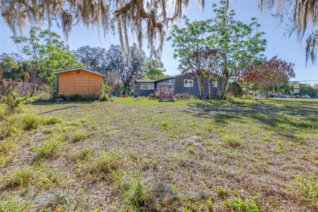 A grassy yard leads to a small orange shed and a dark gray house — 3726 KENILWORTH BOULEVARD, SEBRING, FL