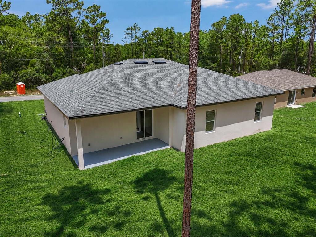 An aerial view of the back of a single-story house with a covered patio — 7565 N SANTOS DRIVE, CITRUS SPRINGS, FL