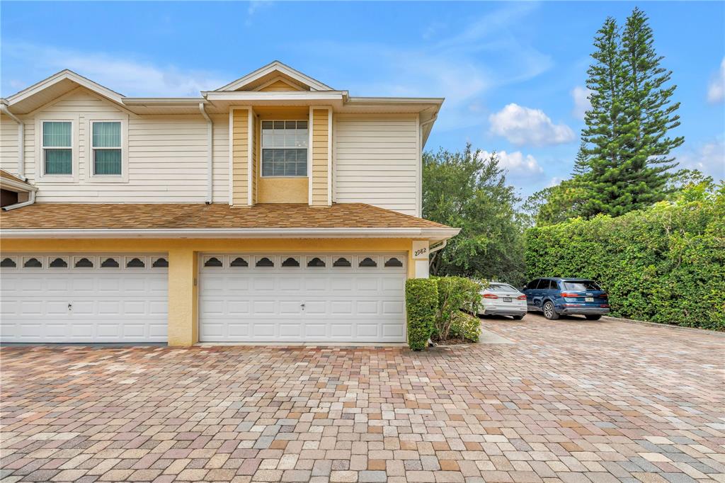 A front entrance with a red door, a "Hello" sign, and surrounding green bushes — 2982 ESTANCIA PLACE, CLEARWATER, FL
