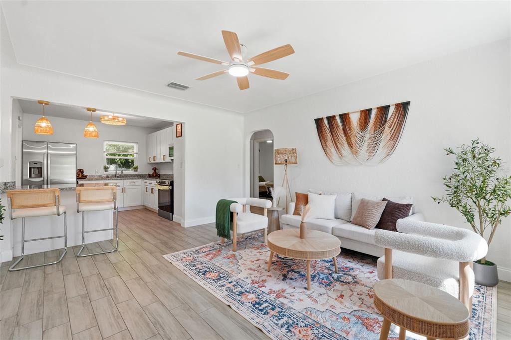 A living room with a sofa and armchairs flows into an open-concept kitchen with stools — 2855 VALENCIA WAY S, ST PETERSBURG, FL