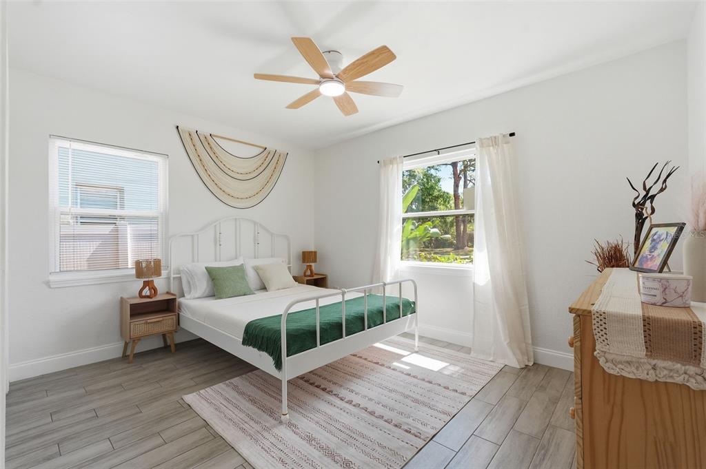 A bedroom features a white metal bed frame, wood-look tile floors, and a ceiling fan — 2855 VALENCIA WAY S, ST PETERSBURG, FL