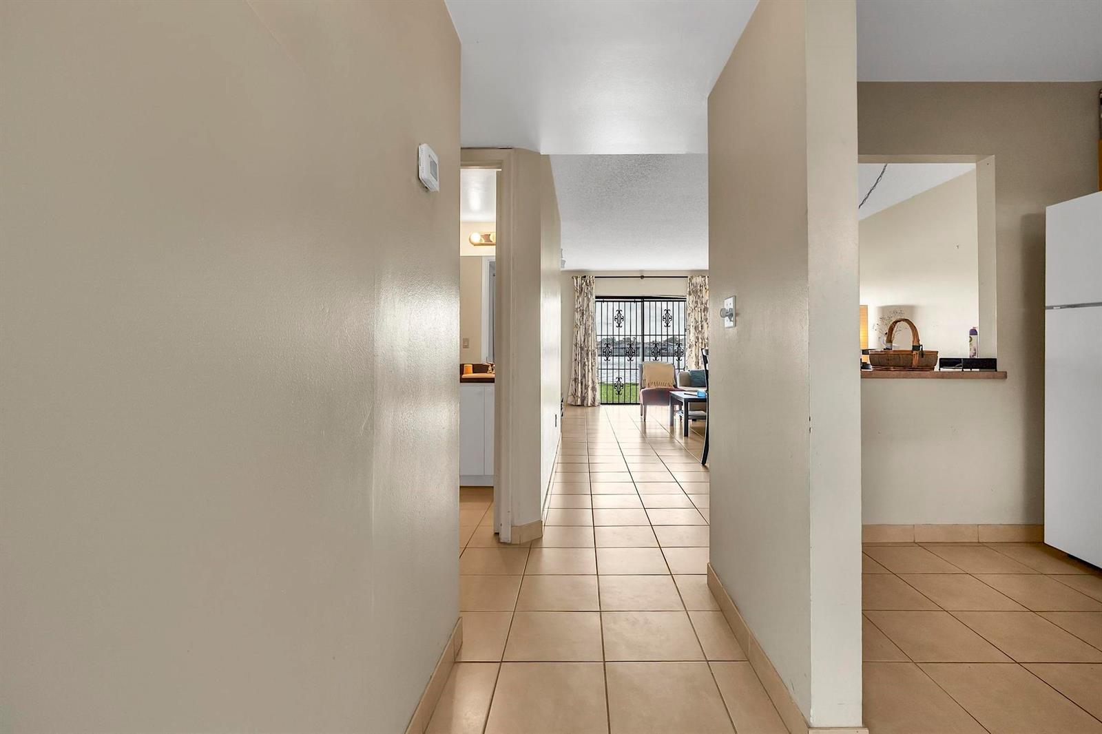A tiled hallway leads from the foreground toward a living area with sliding glass doors — 6715 W 26th Drive # 6, Hialeah FL 33016, HIALEAH, FL