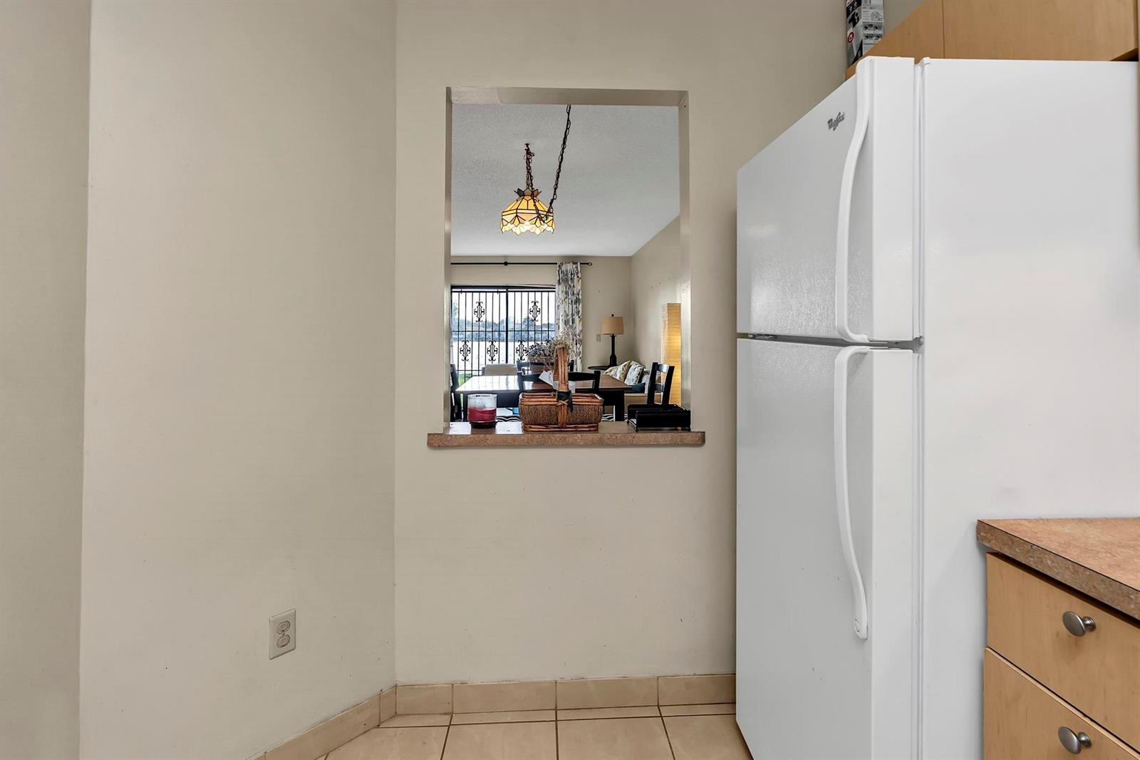 A kitchen view shows a pass-through window looking into a dining area with a chandelier — 6715 W 26th Drive # 6, Hialeah FL 33016, HIALEAH, FL