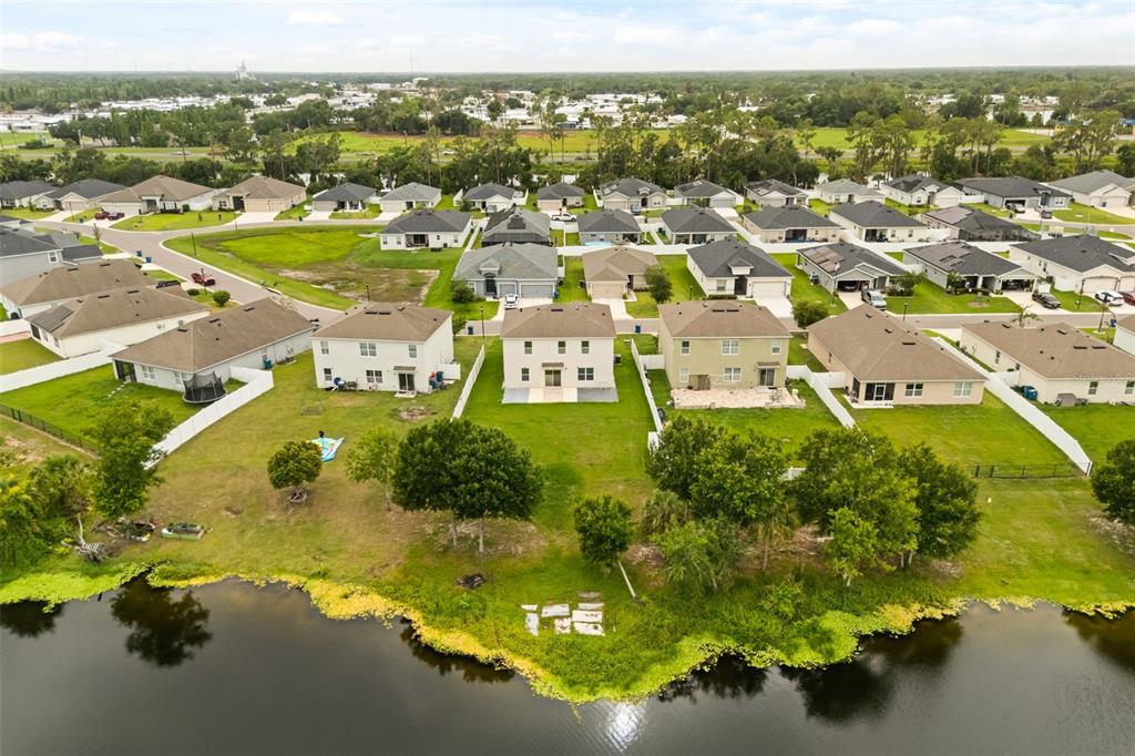 An aerial view shows a suburban neighborhood with houses bordering a lake — 166 ST THOMAS DR, MULBERRY, FL