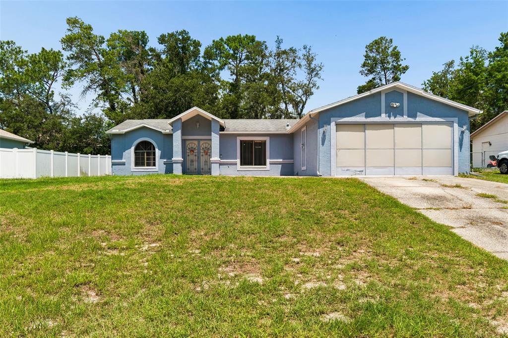 A swimming pool with steps sits inside a screened-in lanai next to a house — 4235 CASTLE AVENUE, SPRING HILL, FL