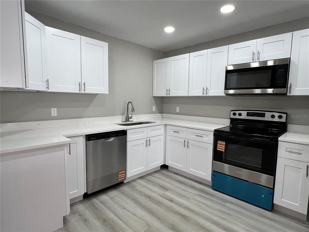 A kitchen features white cabinets, stainless steel appliances, and light-colored wood-look flooring — 4850 N LADYBUG DRIVE, CRYSTAL RIVER, FL