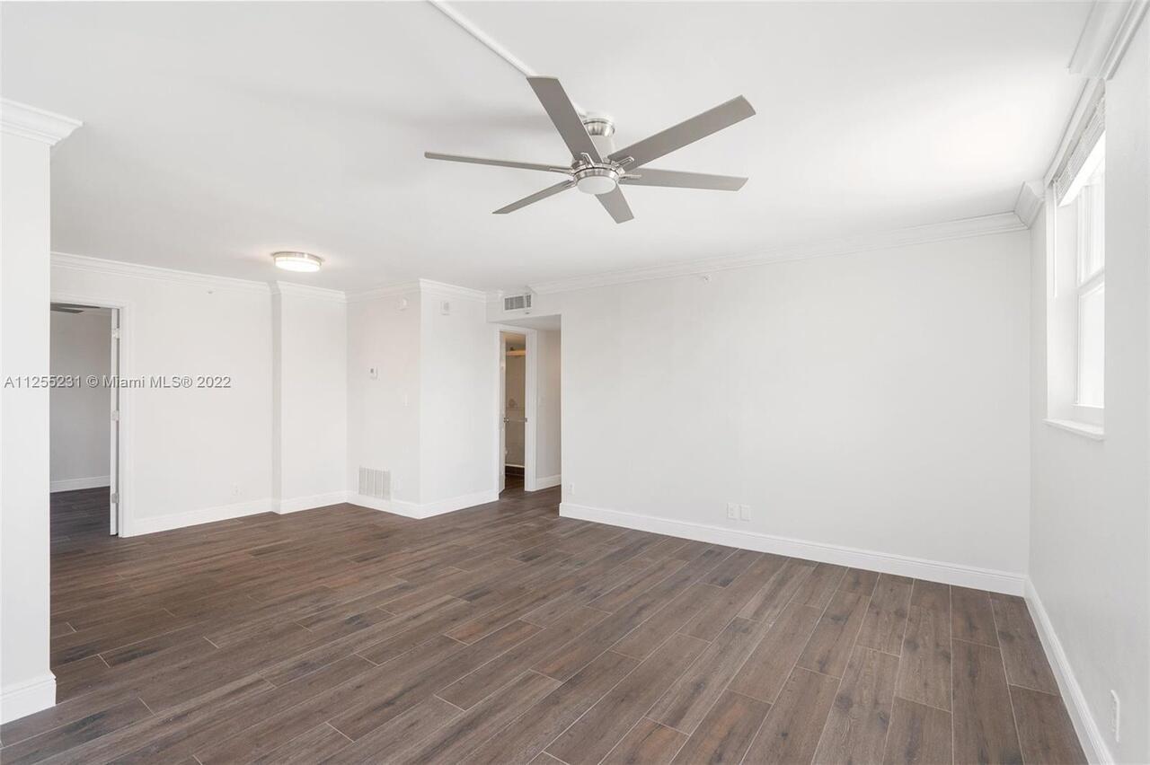 An empty room features dark wood-look flooring, white walls, and a ceiling fan — 1505 N Riverside Drive # 404, Pompano Beach FL 33062, POMPANO BEACH, FL