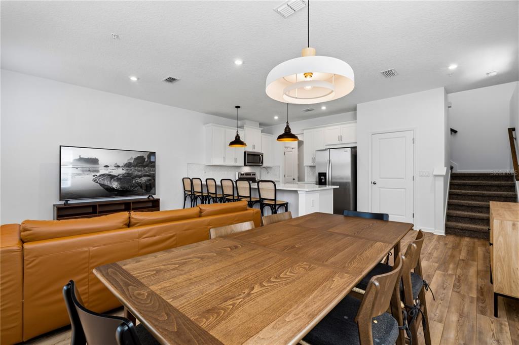 An open-concept living and dining area features a leather sofa, wooden table, and kitchen island — 11653 STRAITS WAY, ORLANDO, FL