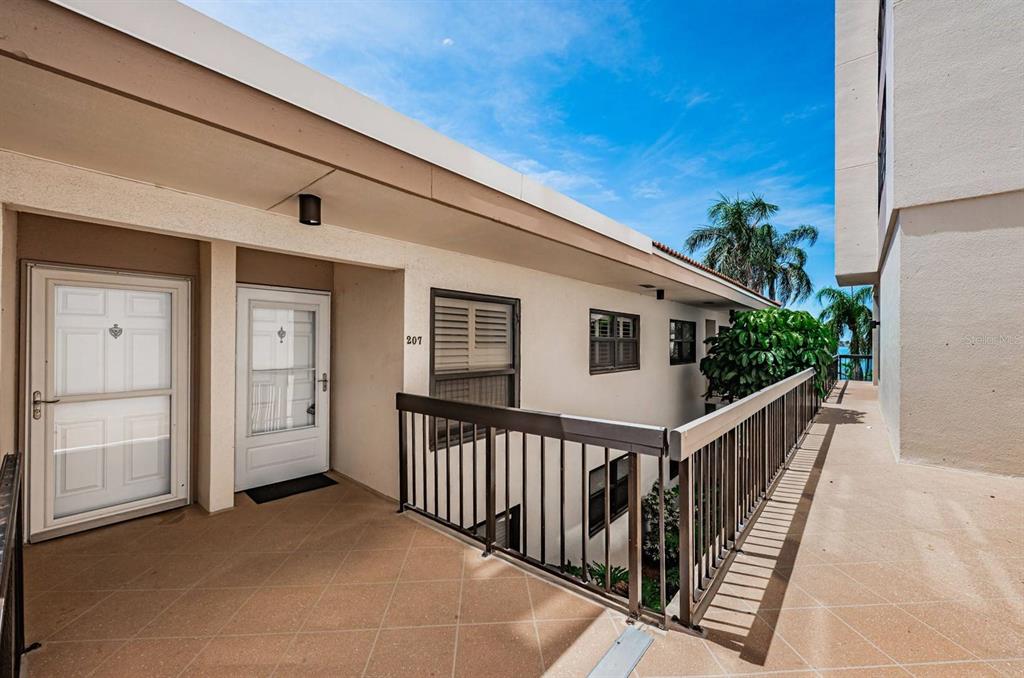 An exterior walkway with a metal railing leads to the entrance of unit 207 — 6291 BAHIA DEL MAR CIRCLE UNIT 207, ST PETERSBURG, FL