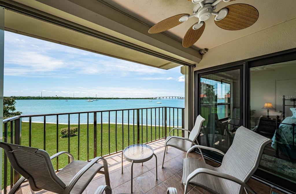 A balcony with outdoor furniture overlooks a grassy lawn and a body of water — 6291 BAHIA DEL MAR CIRCLE UNIT 207, ST PETERSBURG, FL