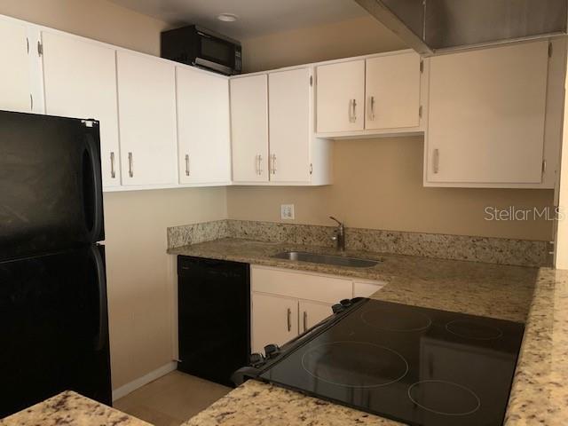 A kitchen features white cabinets, granite countertops, and black appliances — 120 W AMERICA STREET UNIT 7, ORLANDO, FL