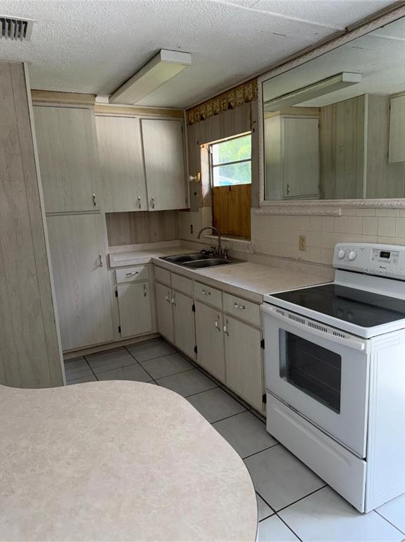 A kitchen features light wood-grain cabinets, a white electric stove, and a tiled floor — 2602 NW 18TH STREET, OCALA, FL