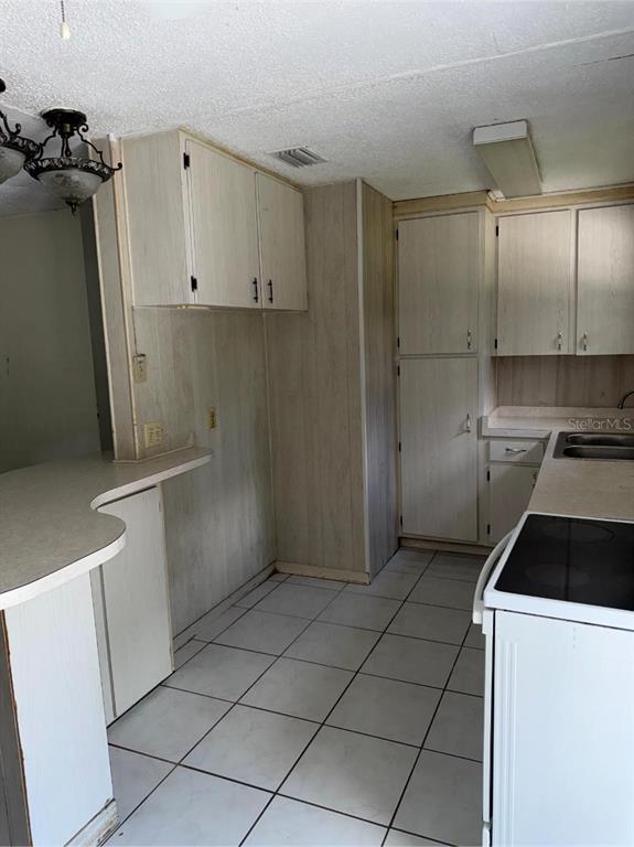 A kitchen features light wood-look cabinets, white tile flooring, and a curved breakfast bar — 2602 NW 18TH STREET, OCALA, FL