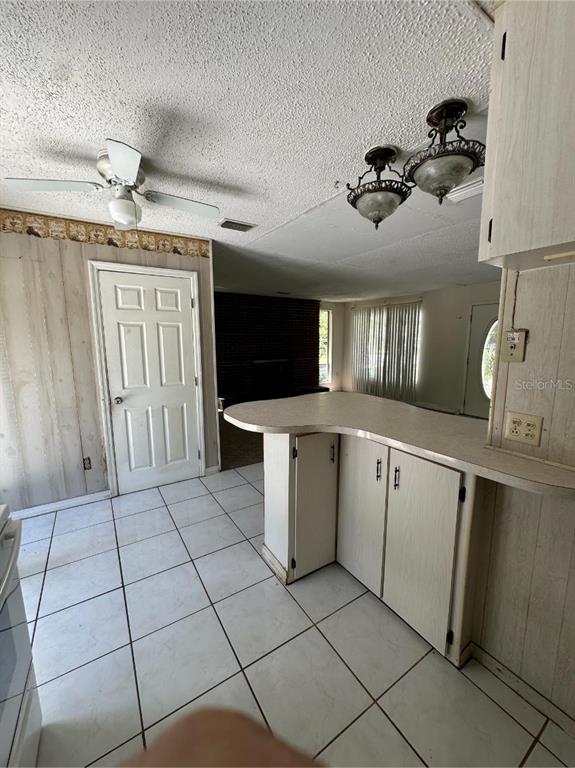 A kitchen with white cabinets, a peninsula, and tiled floors opens into a living area — 2602 NW 18TH STREET, OCALA, FL