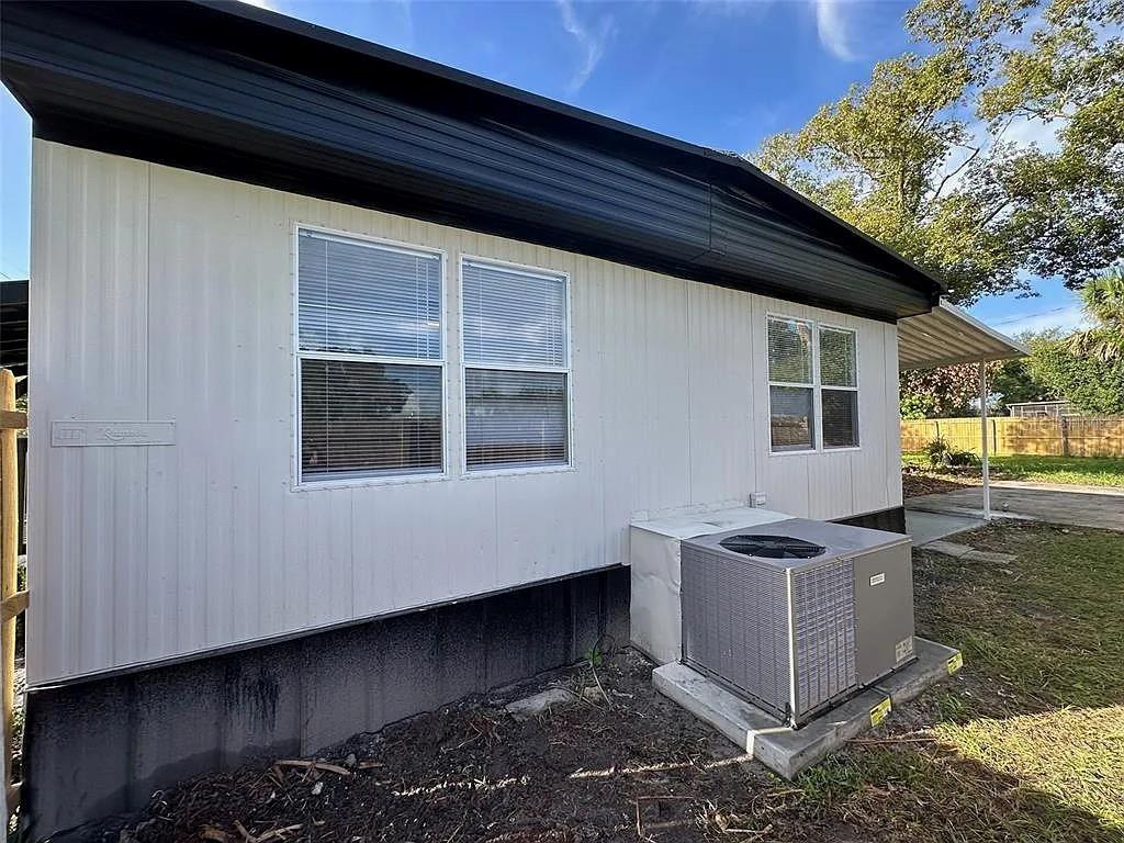 The exterior of a manufactured home features white siding, dark trim, and an HVAC unit — 1704 MISSOURI AVENUE, ST CLOUD, FL
