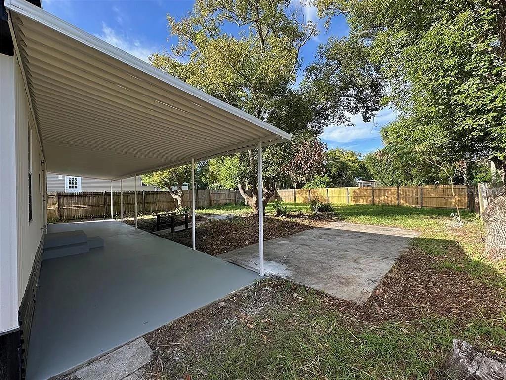 A covered patio with a concrete slab extends from the side of a mobile home — 1704 MISSOURI AVENUE, ST CLOUD, FL