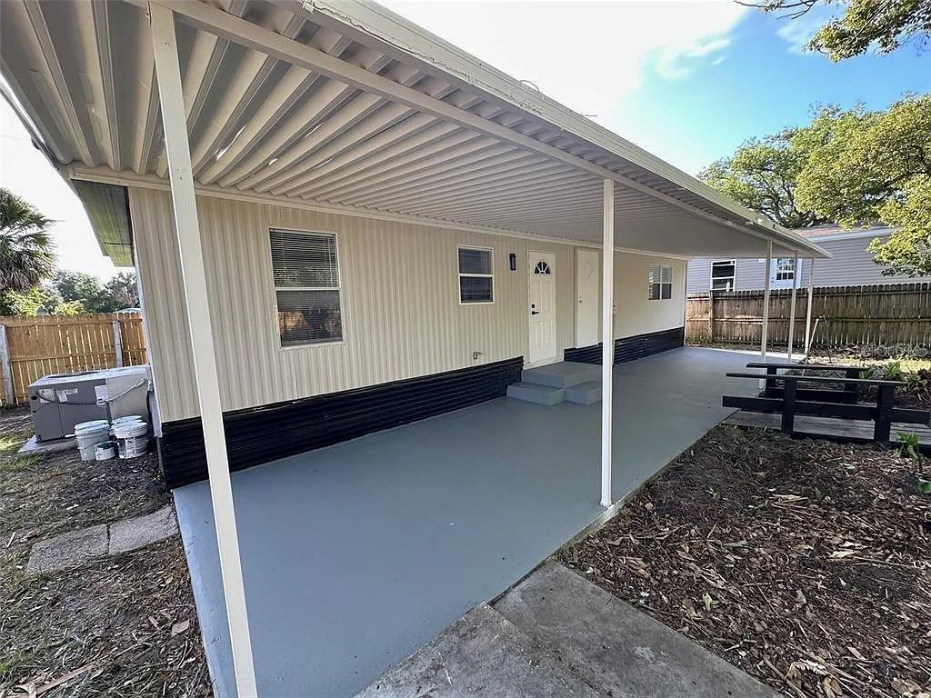 A mobile home exterior features a covered patio, light siding, and a dark base — 1704 MISSOURI AVENUE, ST CLOUD, FL
