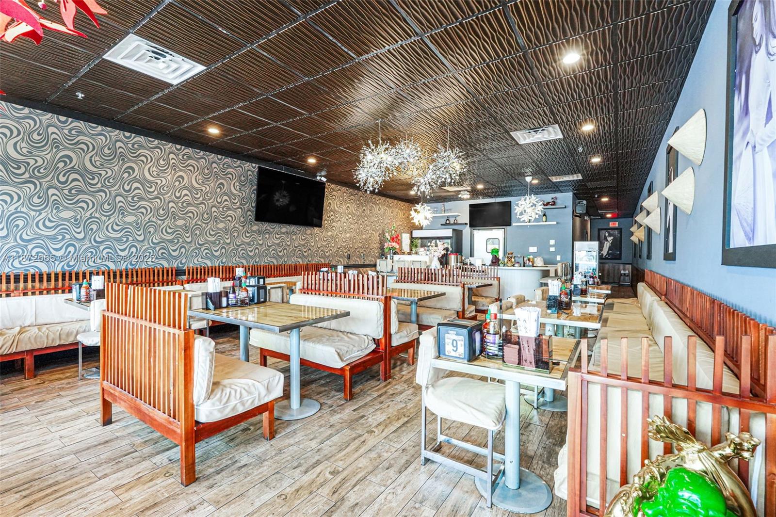 This restaurant interior features wooden booths, patterned wallpaper, a dark textured ceiling, and pendant lights — 16772 sw 88 st, Miami FL 33196, MIAMI, FL
