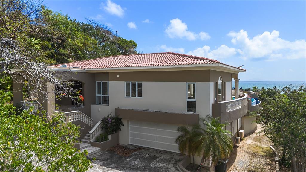 A two-story house with a garage, balcony, and ocean view surrounded by trees — 9 SHELL CASTLE, HUMACAO, PR