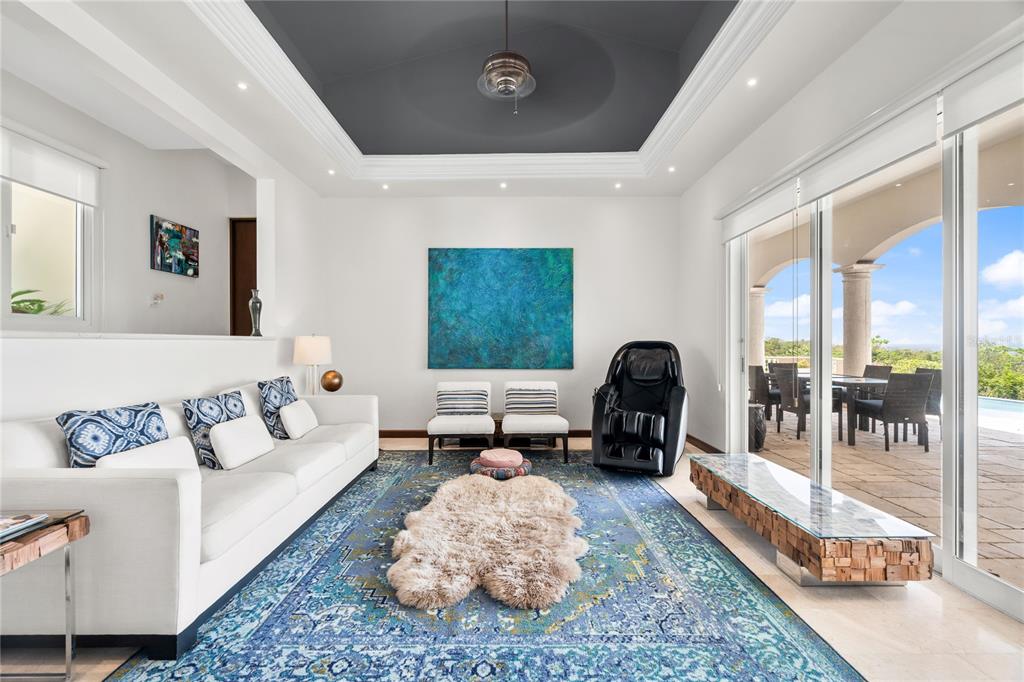 A bright living room features a blue area rug, white sofa, massage chair, and tray ceiling — 9 SHELL CASTLE, HUMACAO, PR