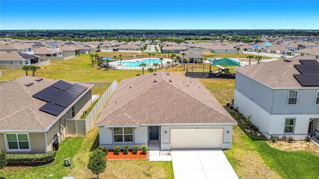 An aerial view of a suburban house with a garage, solar panels, and a community pool — 1539 ASPEN AVENUE, DAVENPORT, FL
