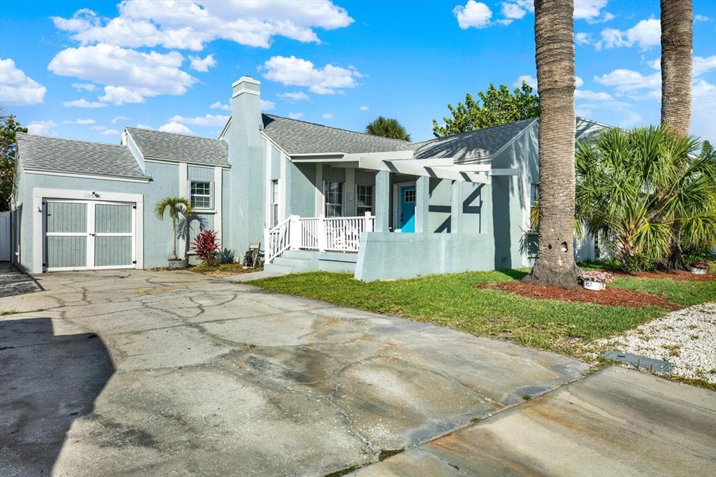 A light blue house with a white pergola, a front porch, and a concrete driveway — 15656 1ST STREET E, REDINGTON BEACH, FL